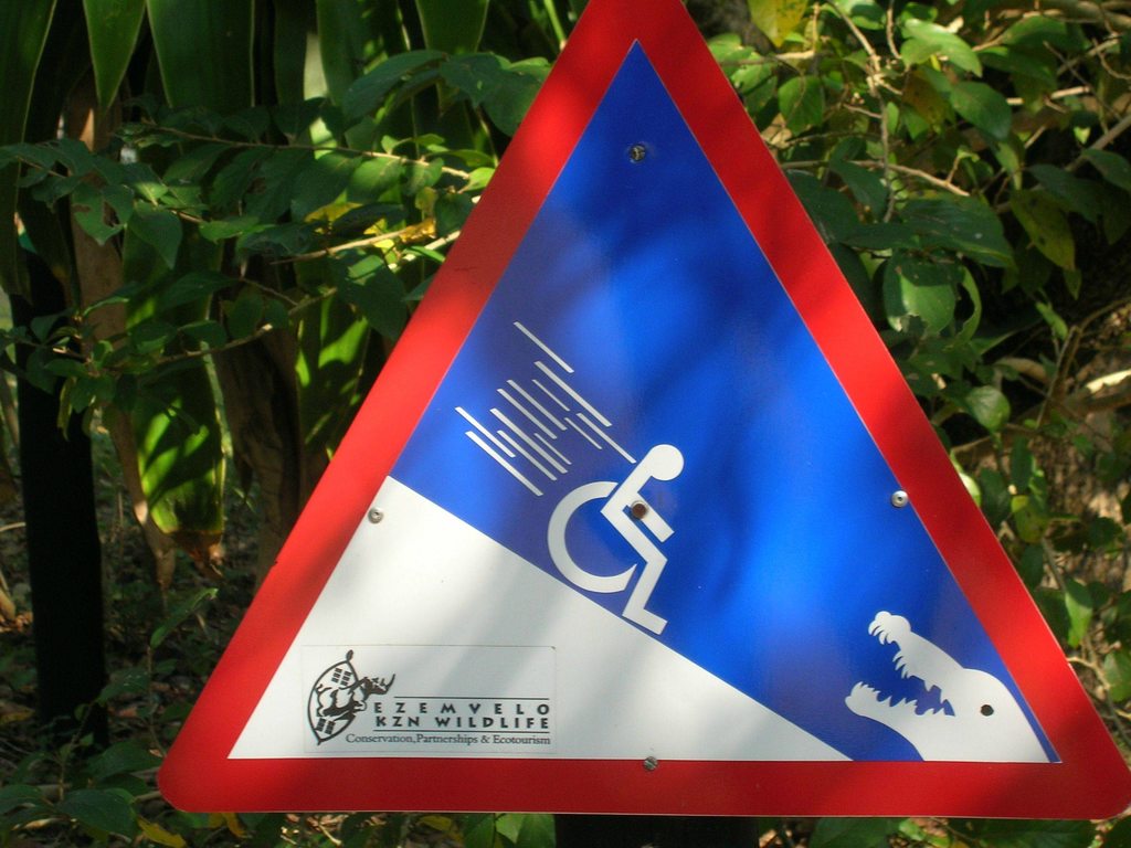 Driehoekig waarschuwingsbord met rolstoel die van helling af glijdt
