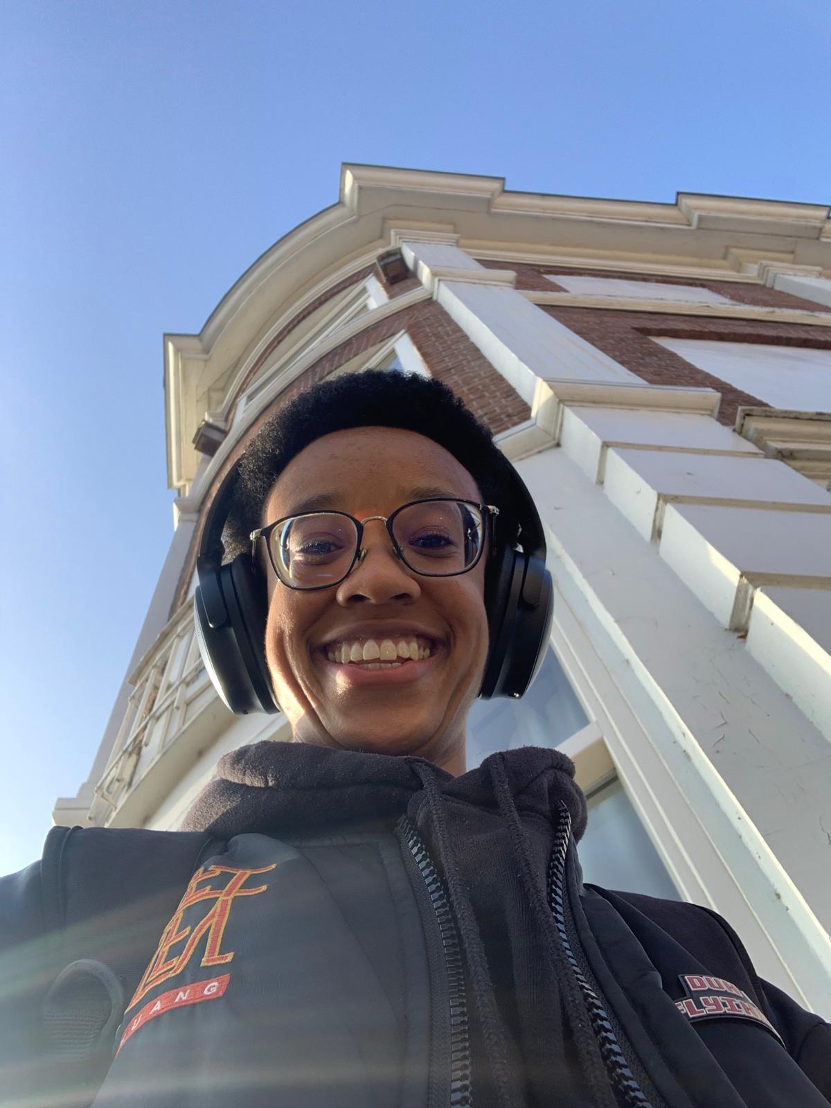 A person with an afro and glasses smiling at the camera